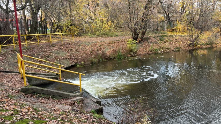 Flowing Water Over a Small Dam in an Autumn Park