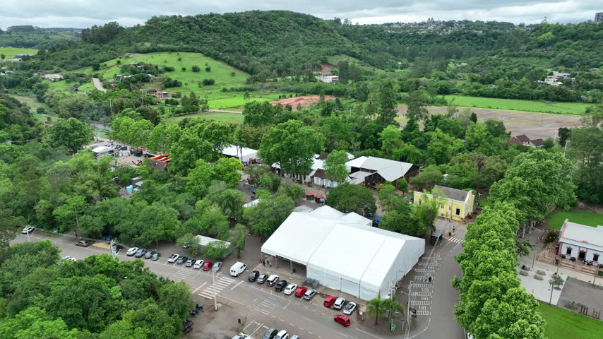 Ivoti traditional neighborhood aerial view over a tree-lined cobblestone street with white tents, parked cars, and green hills in the background