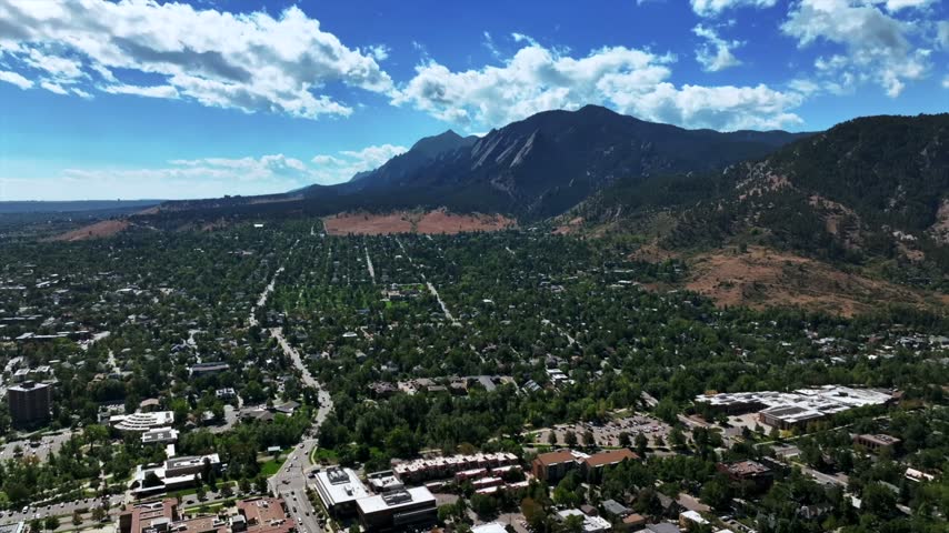 Aerial drone view of Chautauqua Park The Flatirons Mountains late summer fall autumn City of Boulder Colorado Front Range foothills Rocky Mountains sunny morning blue sky clouds forward pan up motion