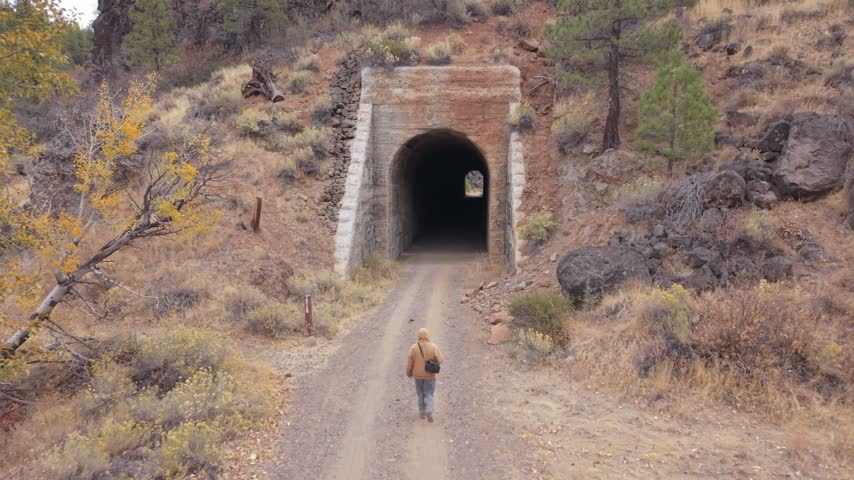 Aerial view of a man walking toward a historic railroad tunnel on the Bizz Johnson Trail in Lassen County, California, on an overcast autumn day.