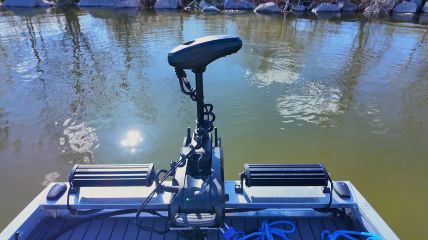 Close up of trolling electric motor rotation at bass boat while boating at the lake. Leisure activity of travelling by boat and recreational use of boat vessel. Sports activities fishing and exploring