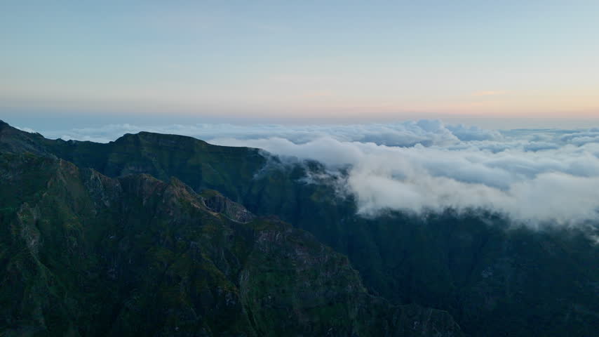 Dawn sky above rugged mountain slopes and low cloud cover. First morning light at start of new day