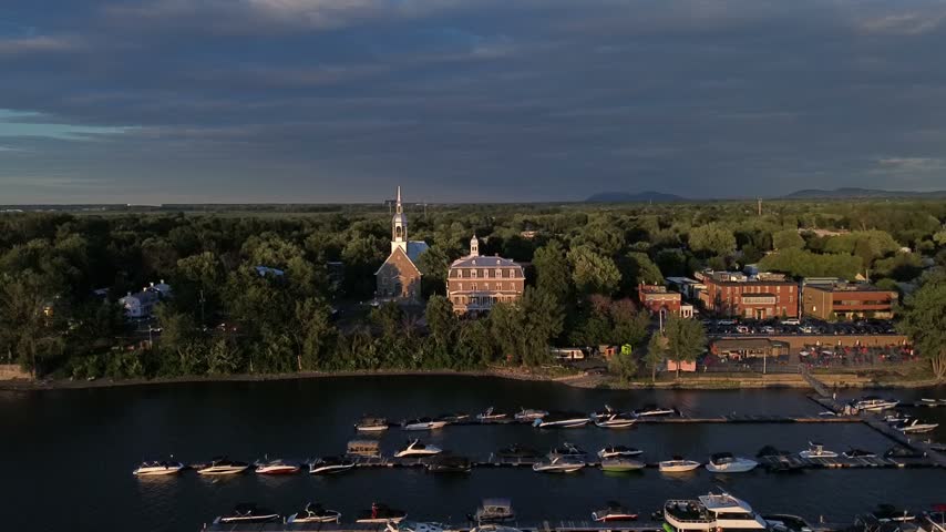 Historic church and marina along a tree lined river in Quebec