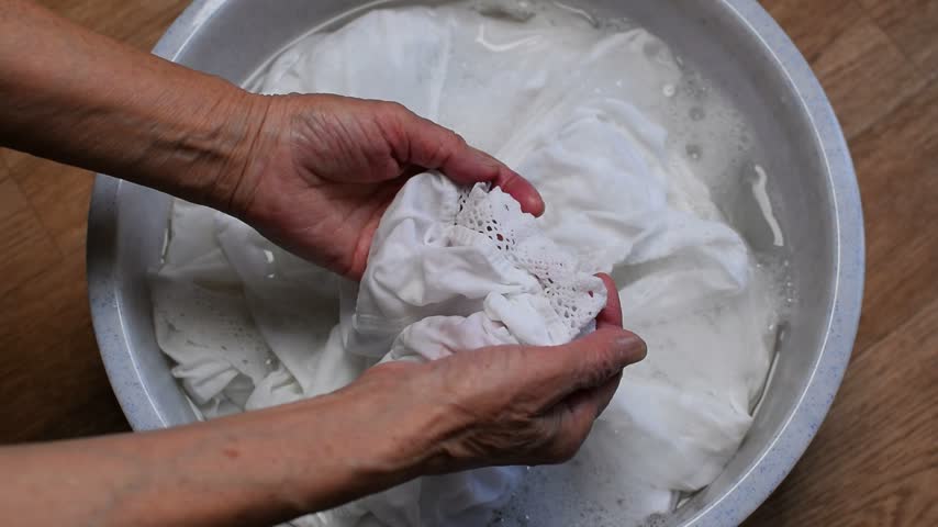 Washing clothes by hand. Woman washes laundry in a basin