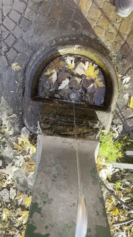 Mini water fountain in a quiet park garden on a sunny day. Peaceful backyard feature and urban landscape element.