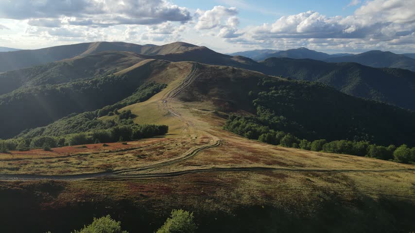 Sunlit mountain valley with rolling green hills in warm evening light