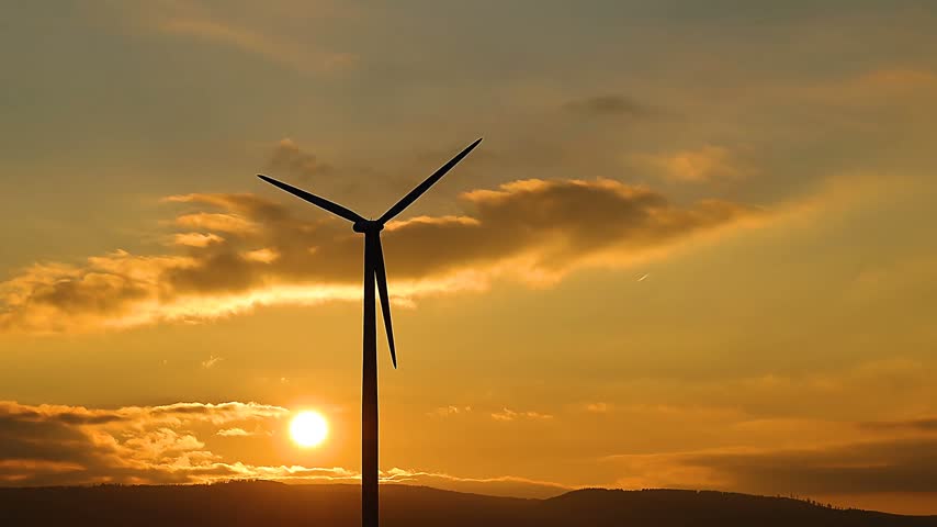 A beautiful view of a spinning windmill set against a stunning sunset backdrop