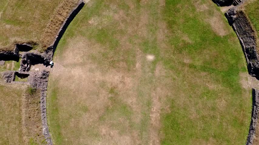 Aerial perspective of Caerleon Roman Amphitheatre in Newport, Wales, where an ancient Roman landmark sits within a modern Welsh landscape.