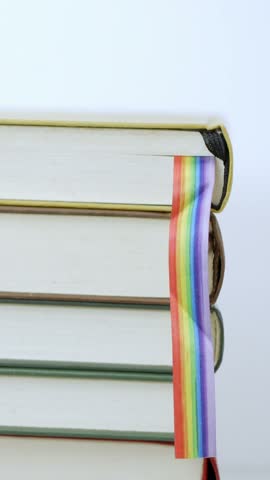 Books.Table and person hands leave with rainbow flag books at library.