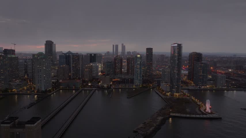 Aerial view of Jersey City waterfront high rises, Hudson River piers and the Waters Soul sculpture at dusk on an overcast evening, New Jersey, USA