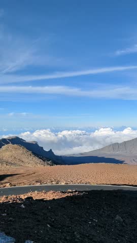 Scenic elevated view of mountain landscape above a sea of clouds under a blue sky.