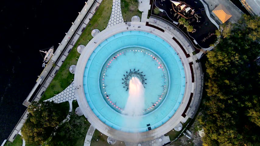 Drone banks above Friendship Fountain while showing the circular fountain and landscaped park in Jacksonville.