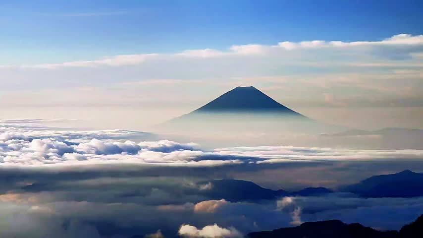 A beautiful view of Mount Fuji in Japan, standing majestically above a sea of ​​slowly moving clouds