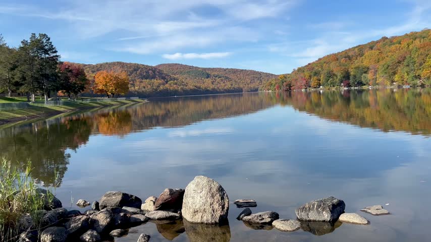 Fall foliage reflects on the calm water of a scenic New England lake.