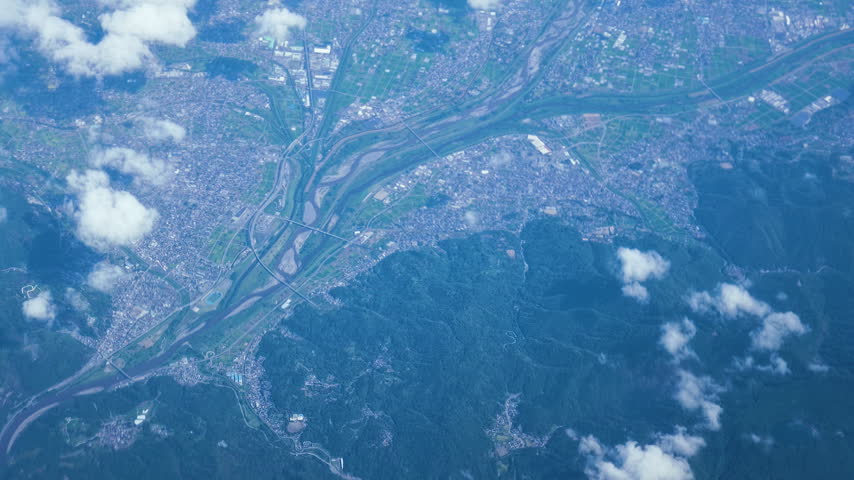 Aerial view of a city landscape covered in clouds and mountains