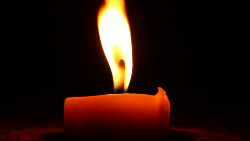 Burning candle in the night. Wind blows and flame shimmers