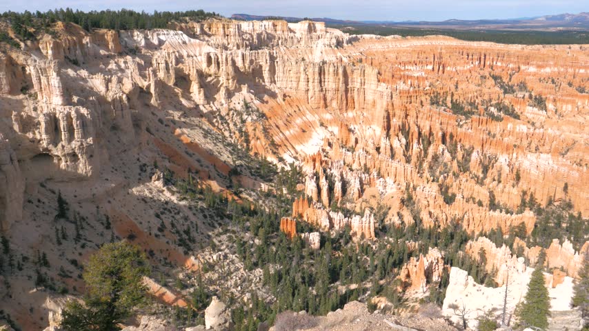 Sunlight illuminating orange hoodoos and sandstone red rock spires in bryce canyon amphitheater, showing natural geological formations under bright blue sky on a sunny autumn day