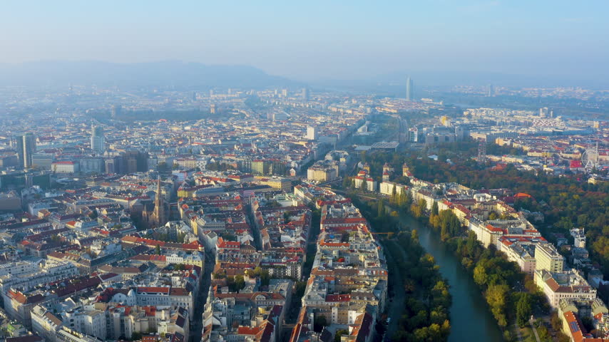 Aerial view of Vienna, Austria, featuring the Danube Canal, tree-lined embankments, dense historic city blocks and Prater