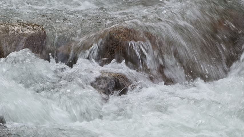 Mountain stream cascades in close-up over rock creating white water splashes