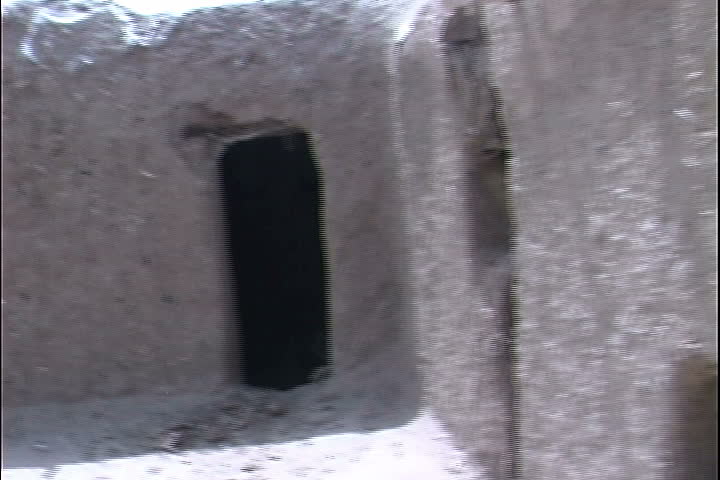 Walk around mud brick building and enter single-room dwelling, tilt up to thatched ceiling in Bannu District, Pakistan.