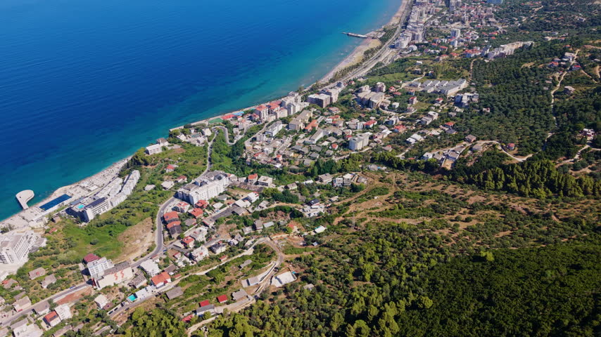 Aerial drone view of Vlora Bay and the coastal city along the blue Adriatic Sea, Albania, with hills rising behind the shoreline