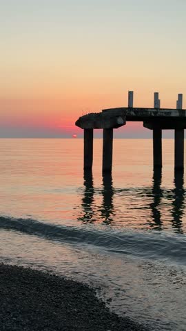 Scenic view of a decaying dock structure over peaceful ocean water at dusk