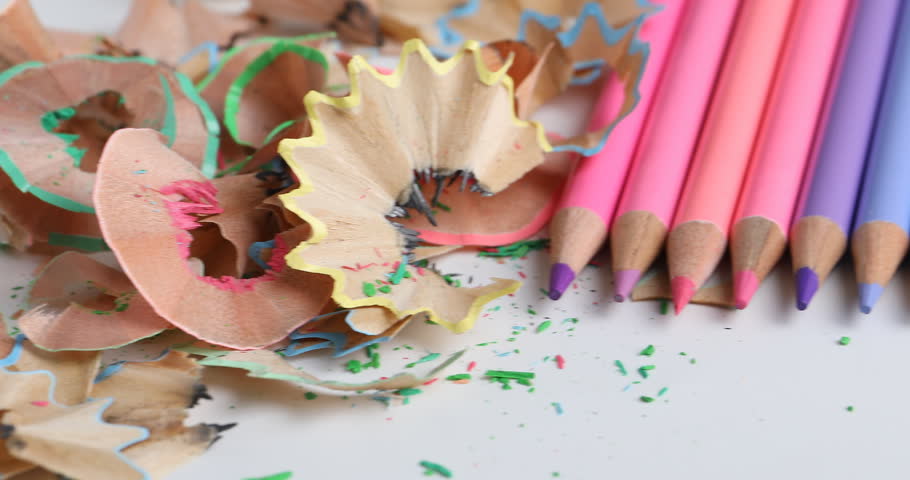 Sharpeners with shavings and colorful pencils on table, closeup. Camera moving right