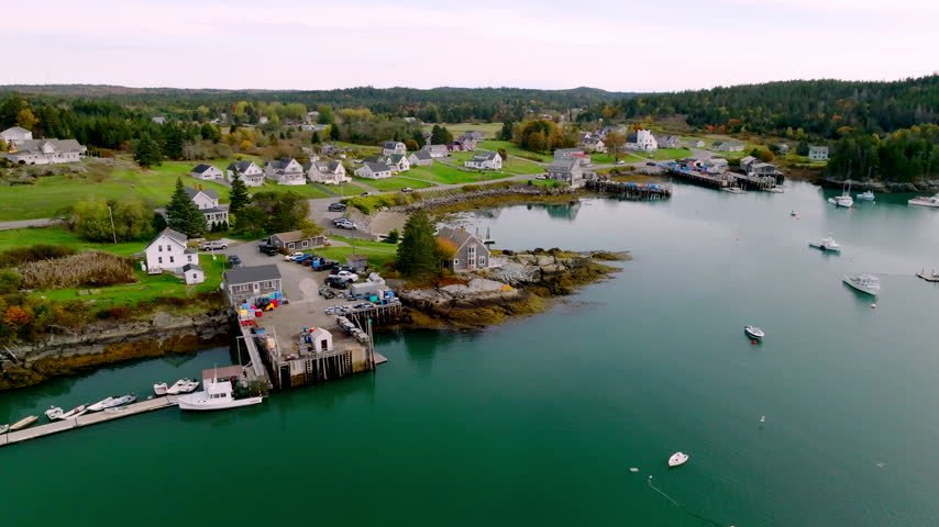 Lobster boats moored by a working wharf stacked with gear in Cutler Harbor, Maine