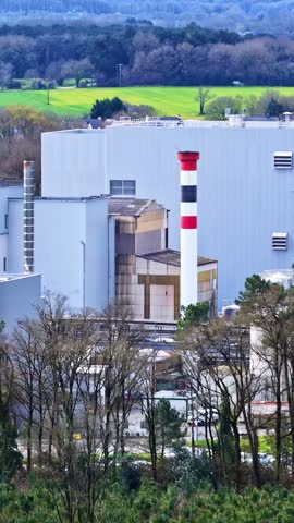 Vertical telephoto shot of a factory chimney and metal clad plant buildings