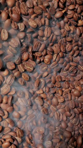 Close up of seeds of coffee. Fragrant coffee beans are roasted smoke comes from coffee beans.