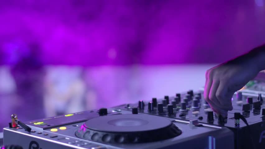 DJ at his deck controlling sound volume in night club performance