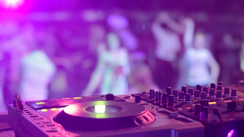 DJ hands and equipment during night club party with dancing people