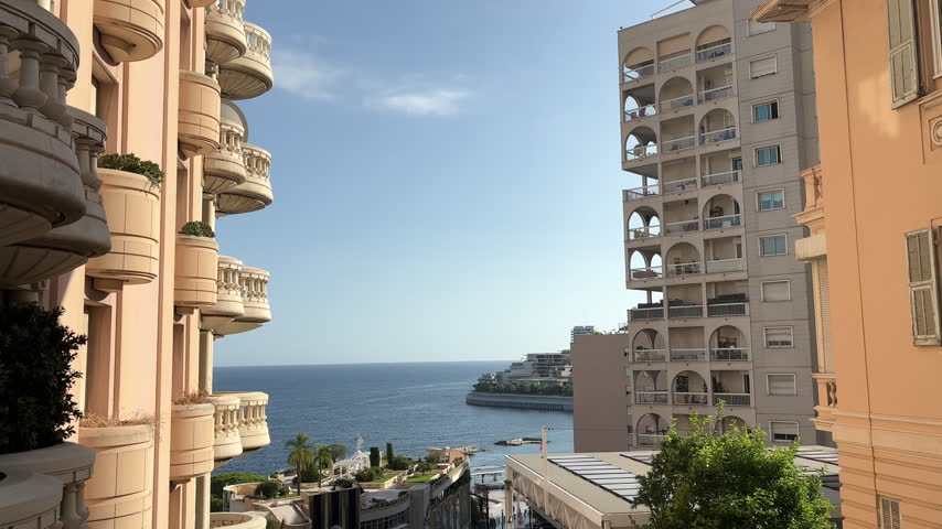 Scenic view of Monaco featuring elegant luxury apartment buildings with ornate balconies, Mediterranean Sea views, upscale waterfront architecture, and the glamorous French Riviera coastline.