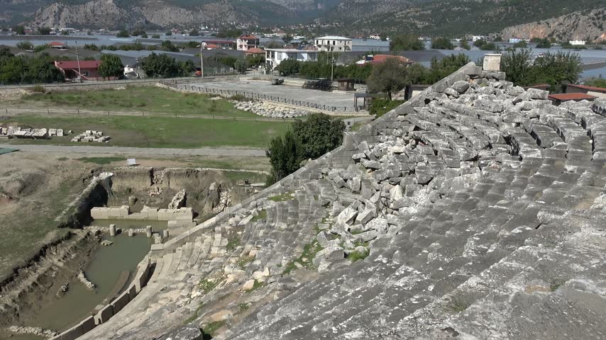 Fethiye, Mugla, Turkey - 21st of October 2026: Ancient Letoon theater with modern village and greenhouses
