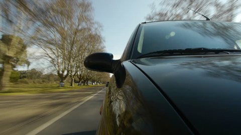 Driving a car, windshield reflection. Hood side reference. Mounted camera, front view. Black car ride. Country road, trees on the side, blue sky, day. Fast Speed / Time-Lapse. HD.