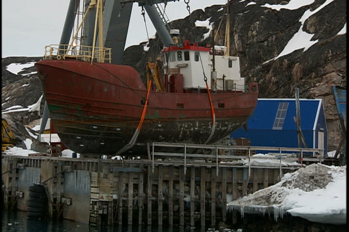  Fishing boats in dry dock along snowy coast of bay in Greenland.
