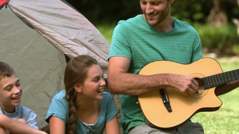 Father playing guitar for his family in slow motion