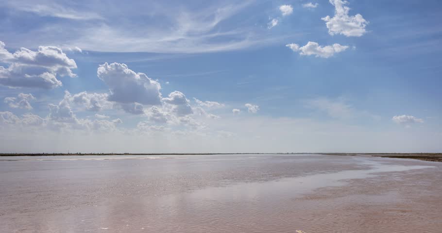 Time-lapse of the Yellow River flowing under a blue sky with fast-moving white clouds, Bayantohai Town, Inner Mongolia, China.