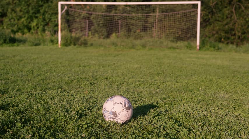 Footage captures a casual soccer moment. Ball rests on grass, waiting for action. Player kicks the ball toward the goal. Goalkeeper stands ready, anticipating the shot
