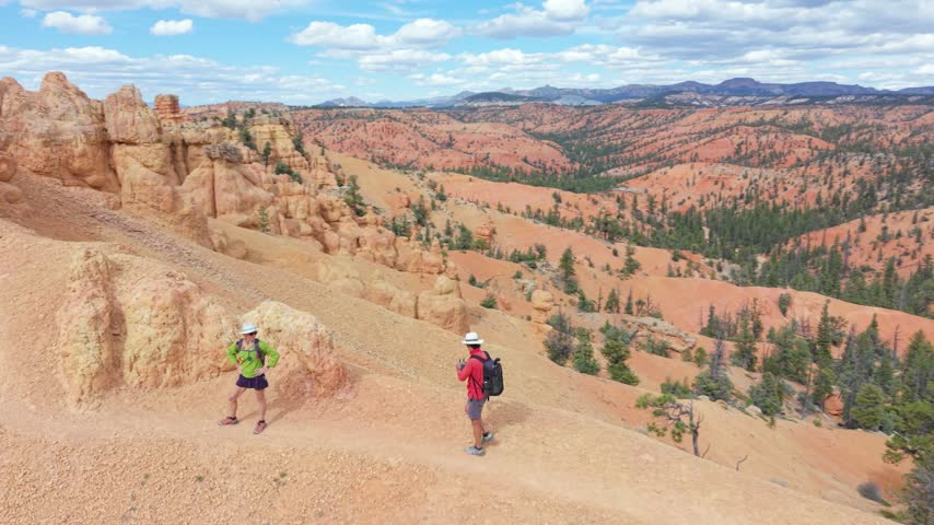 Aerial view of man and woman hiking on Buckhorn Trail surrounded by hoodoos near Bryce Canyon in Utah. The trail offers stunning views