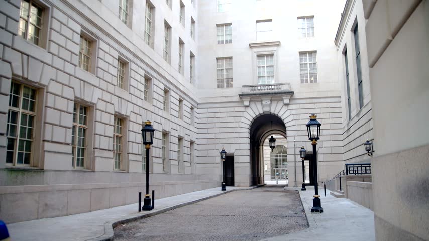 Stone government buildings frame a paved courtyard and central archway in Washington.