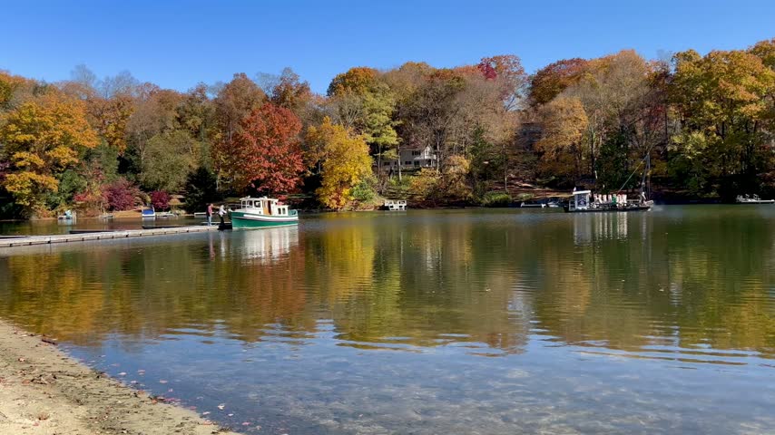 Boats docked on a scenic lake during autumn.