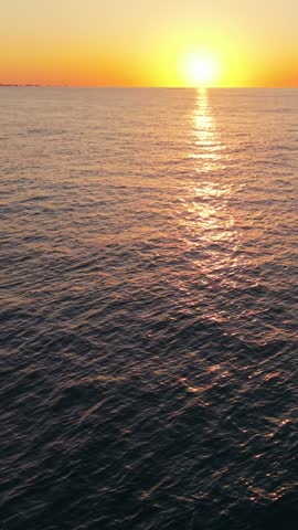 Vertical screen. Sunset over calm ocean waters at Myrtle Beach, South Carolina, with vibrant colors reflecting on the water