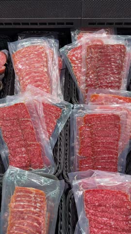 Vacuum sealed raw meat portions arranged in supermarket display trays, showing sliced and ground beef packaging with red textures, transparent plastic wrapping, and retail food merchandising video