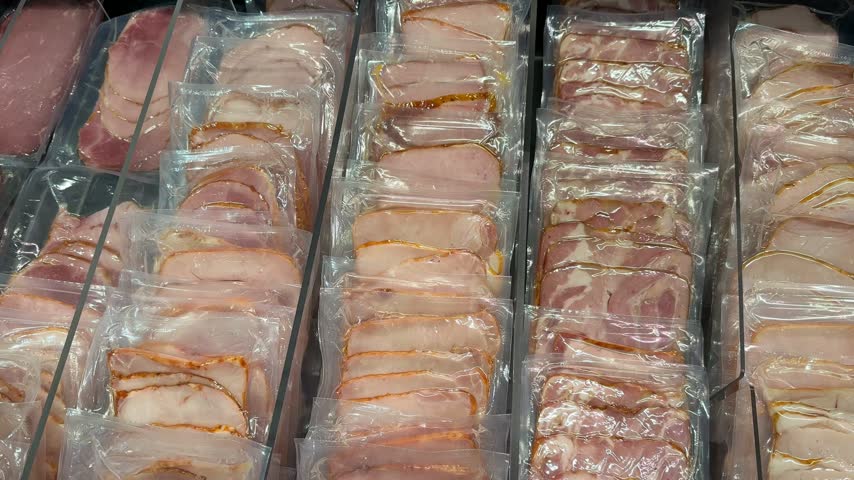 Rows of sliced deli meat sealed in clear plastic packages, arranged in refrigerated display trays for grocery shopping, food retail, packaging, storage, and supermarket merchandising video video