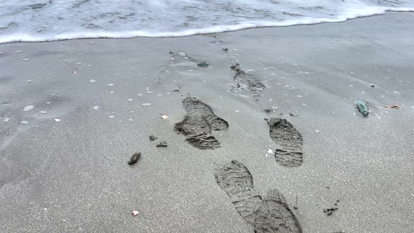 Waves washing onto a sandy beach under a cloudy sky