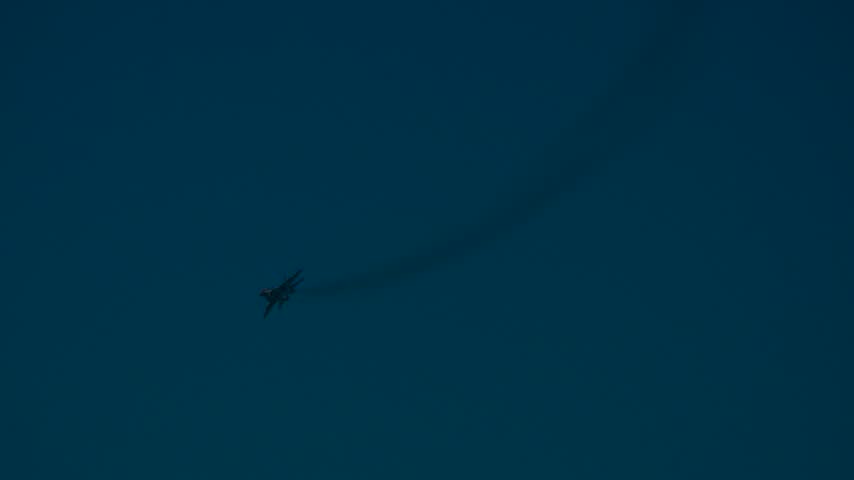 Fighter jet flying low past the pier on the beach