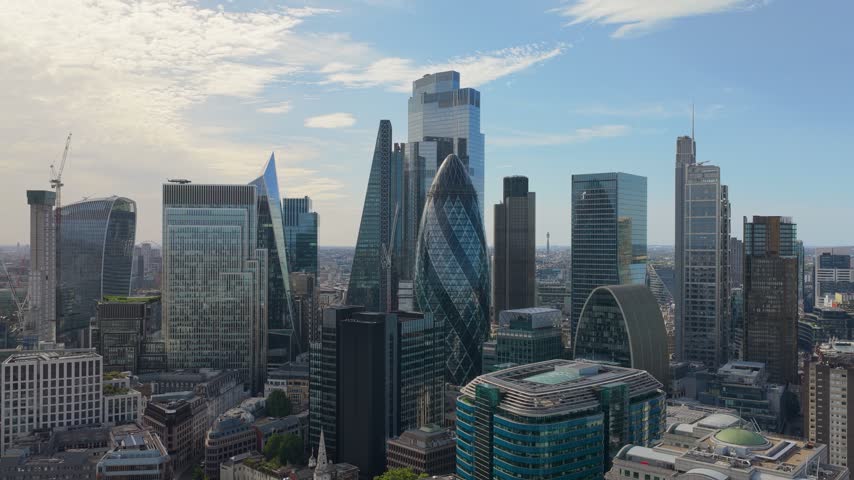 Aerial view of London showcasing famous skyscrapers, modern architecture, and bustling city streets under a clear blue sky