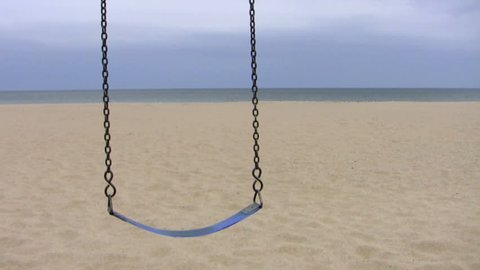 A lone swing at an empty beach on a cloudy gray day