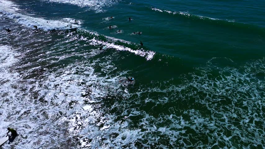 Aerial view of surfers paddling out in the ocean, Algarve, Portugal